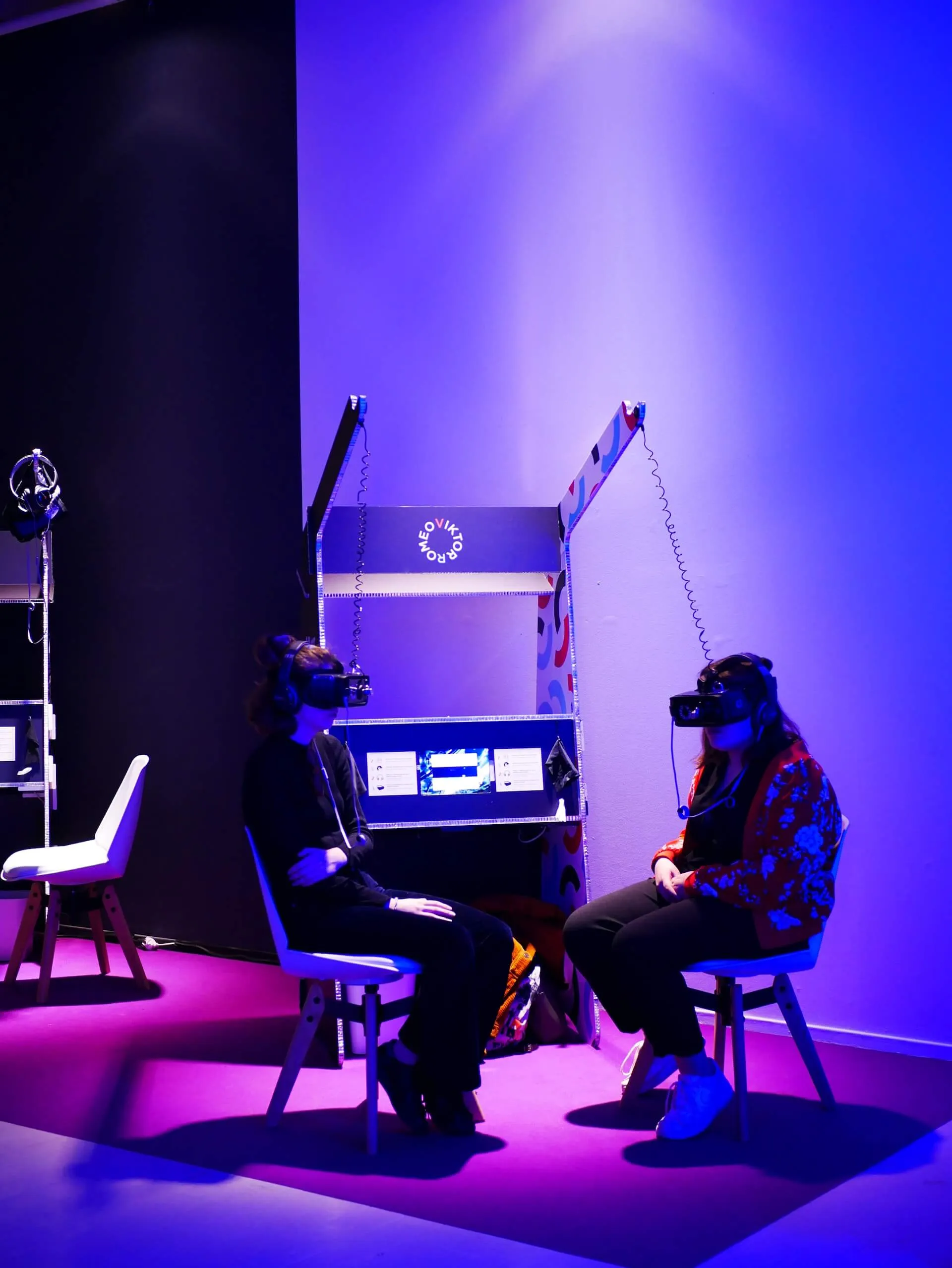two people sitting experiencing VR headsets.